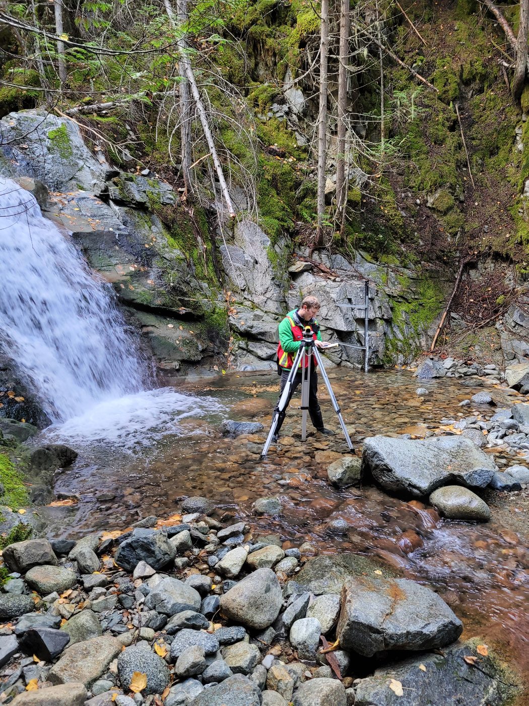 Surveying at a creek monitoring site below a waterfall