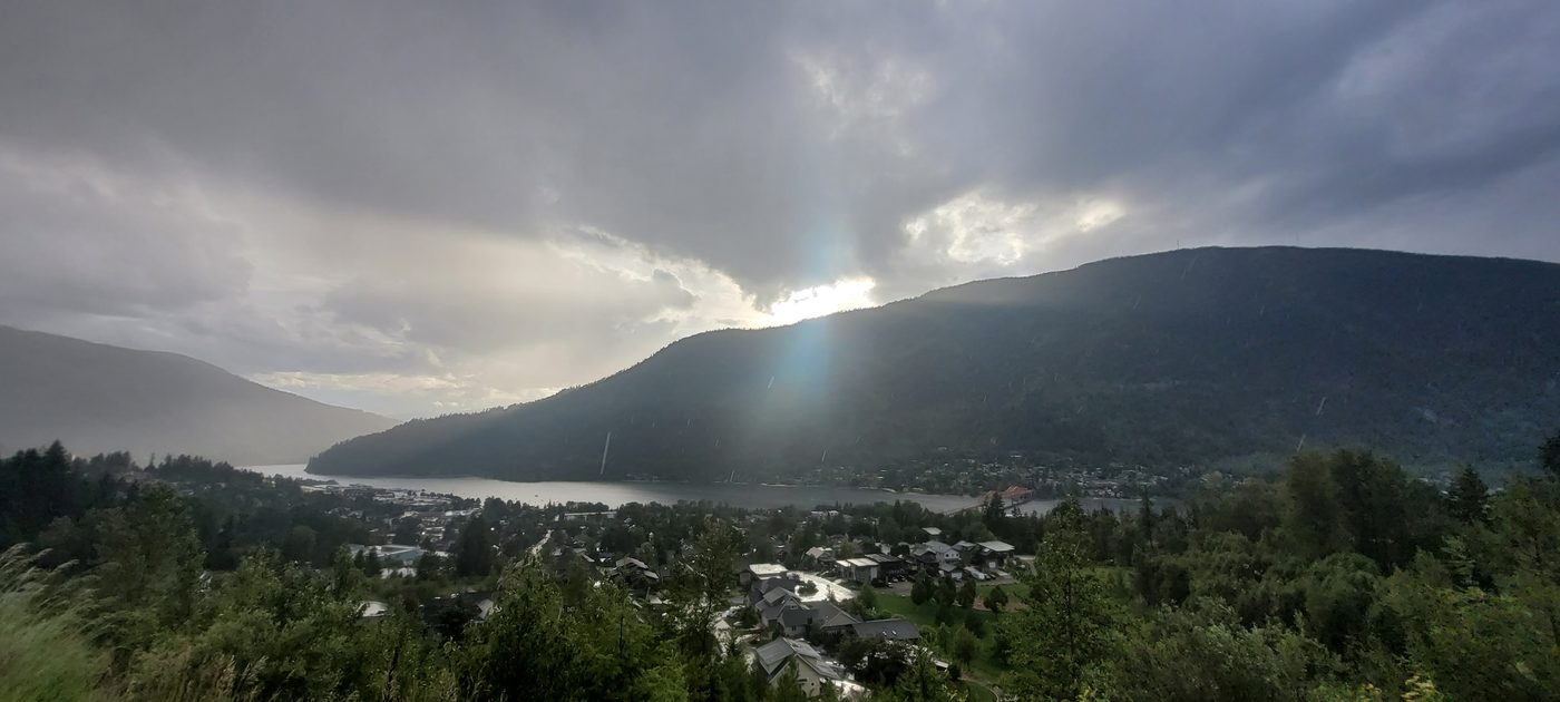 A Kootenay valley town and mountains under cloud