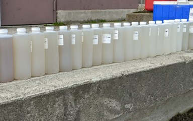 A row of water quality sample bottles, from cloudy to clear